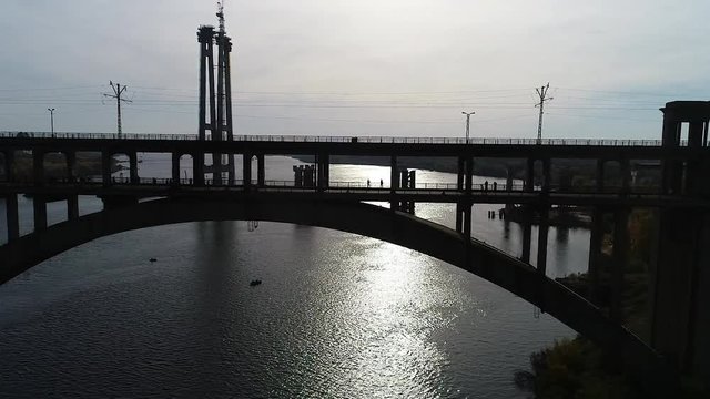 The span on the quadcopter parallel to the bridge on which the silhouettes of the running half-marathon athletes are shot