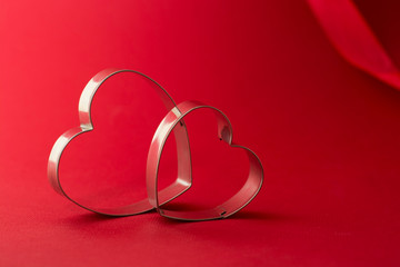 Happy Valentine's Day Greeting card. Two red heart shaped cookie cutters on beautiful red background.