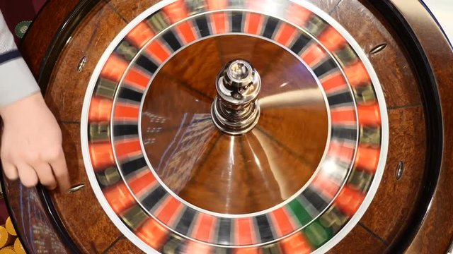 Casino theme. Top view on roulette in motion, white ball spinning. Bad luck and Good luck concept. Roulette wheel running. City nightlife entertainment. Dealer hand moves the roulette. hd