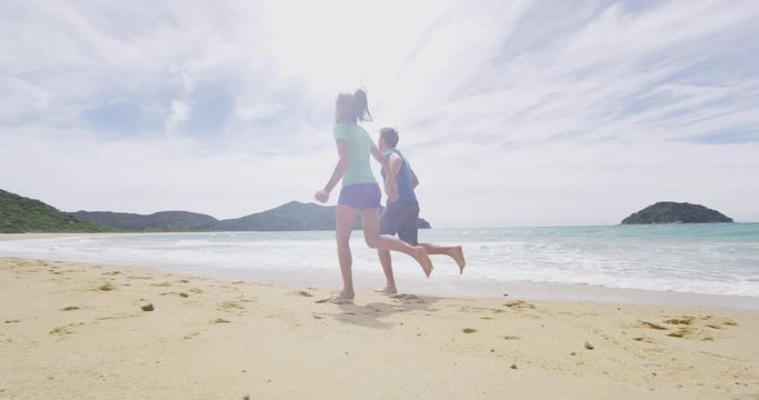 Couple running on beach in love having fun holding hands in New Zealand Abel Tasman National Park. New Zealand travel vacation lifestyle with people on Onetahuti beach, Tonga Bay. RED EPIC SLOW MOTION