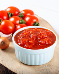 Tomato sauce with garlic, basil and spices in a white bowl on white background