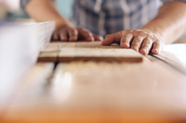 Fototapeta na wymiar Woodworker sawing a plank of wood in his carpentry workshop