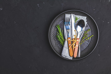 Rustic vintage set of cutlery knife, fork and spoon in black ceramic plate