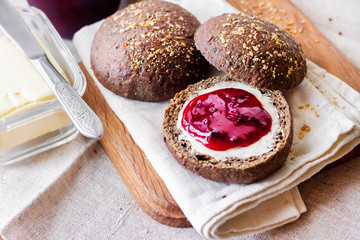 Homemade rye buns with linseeds, sesame and white poppy seeds served with butter and Jostaberry jam