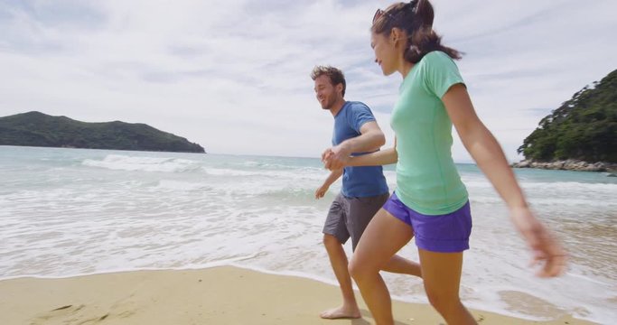 New Zealand beach travel vacation couple on Onetahuti beach running having fun in love holding hands enjoying holidays in Abel Tasman National Park, Tonga Bay, New Zealand. RED EPIC SLOW MOTION.