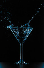 Cocktail martini glass splash on black background