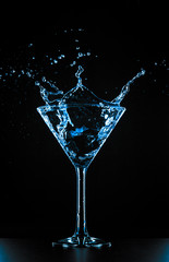 Cocktail martini glass splash on black background