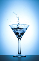 Cocktail martini glass splash on white and blue gradient background