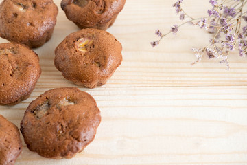 Photo of homemade muffins with dry flowers on wooden background. Homemade baking. Chocolate muffins with bananas. Chocolate banana cake