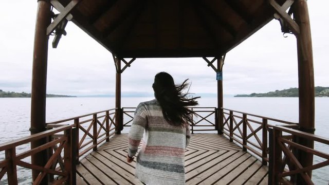 Woman runs towards the end of the wooden pier, Llanquihue lake, Chile. 4k
