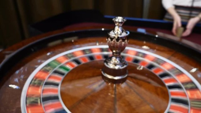 Casino theme. Top view on roulette in motion, white ball spinning. Bad luck and Good luck concept. Roulette wheel running. City nightlife entertainment. Dealer hand moves the roulette. hd