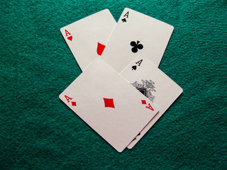 The four aces of a poker deck on a green mat