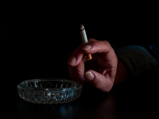 The hand of a woman smoking a cigarette and one ashtray