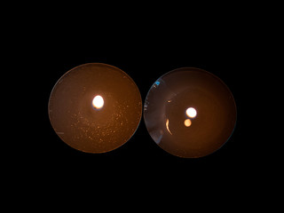 Two lighted candles with an orange flame and isolated on a black background