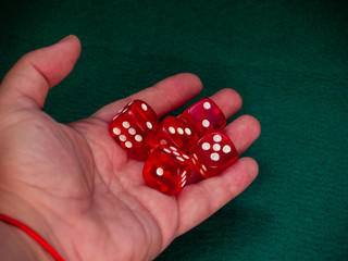 The hand of a person throwing the dice on a green carpet