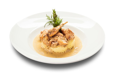 quail in a sauce with a side dish of mashed potatoes on a round white plate