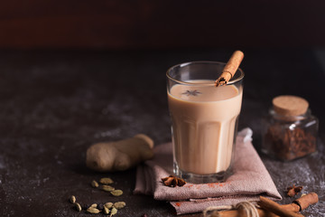 Masala chai tea on the dark background. Hot indian beverage with spices. Image with copy space - obrazy, fototapety, plakaty