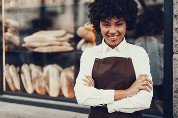 Attractive lady standing near bakery shop and smiling - obrazy, fototapety, plakaty