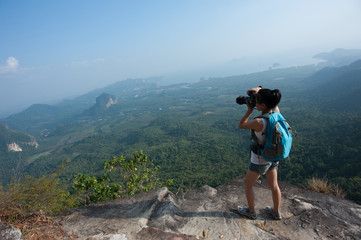 young woman photographer taking photo at mountain peak