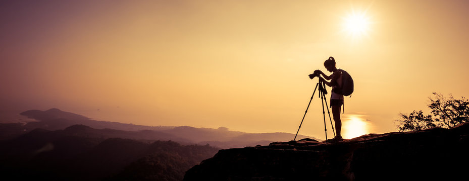 woman photographer taking photo on sunset mountain peak