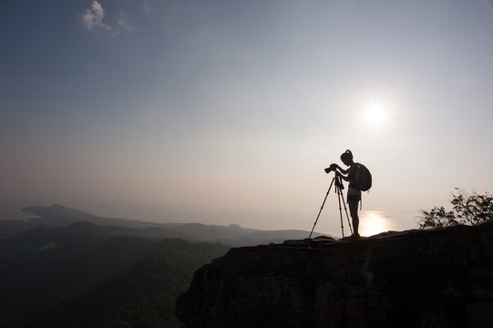 woman photographer taking photo on sunset mountain peak