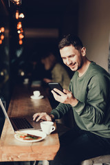 Handsome man working in small cafe in morning