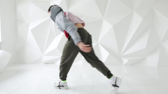 Professional male breakdancer performs unreal dance moves on the floor in a white studio