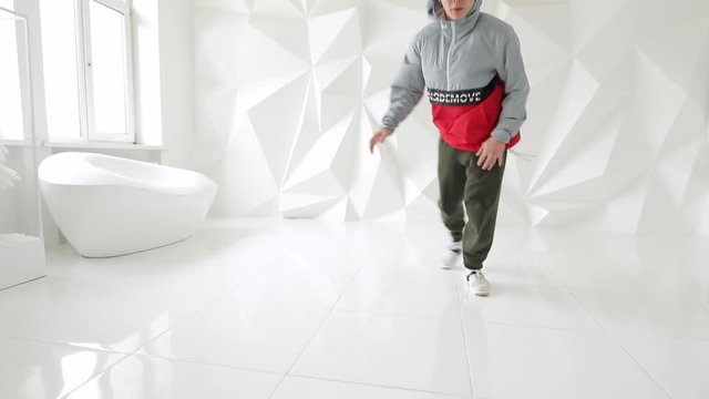 Professional male breakdancer performs unreal dance moves on the floor in a white studio