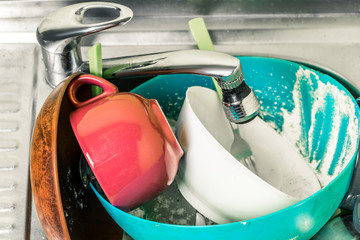 dirty dishes, cups, plates, spoons in the sink