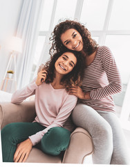 Smiling sister in grey leggings sitting near her older sister