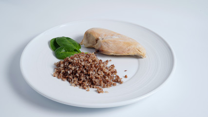 Chicken fillet, buckwheat, spinach leaves are on a white plate         