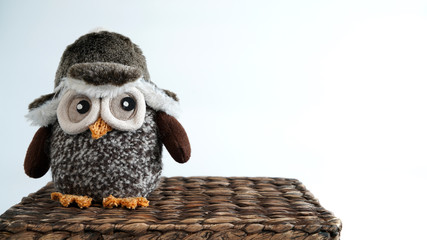 Obraz premium Toy owl sitting on a wicker box 