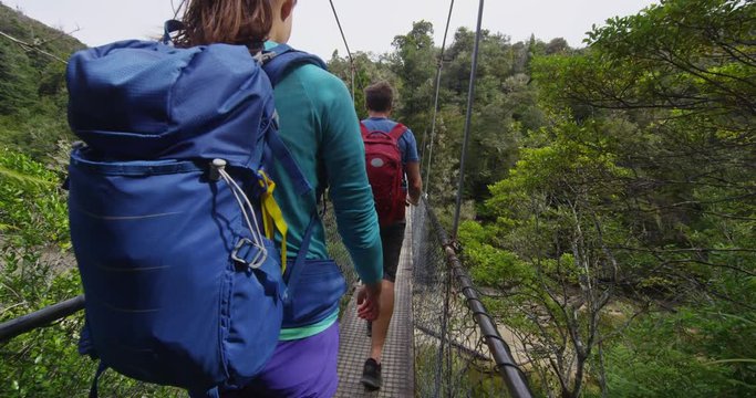 Tramping. People hiking in New Zealand, Abel Tasman National Park. Young couple backpacking crossing swing bridge over Falls River. Shot on RED EPIC in SLOW MOTION.