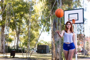 Young woman enjoys on the basketball court with her ball
