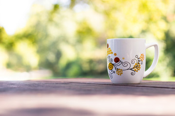 Cup coffee and sunny trees background 