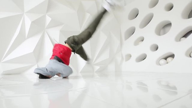Professional male breakdancer performs unreal dance moves on the floor in a white studio