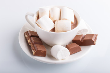 a cup of hot cocoa with marshmallow and milk chocolate  isolated on white.