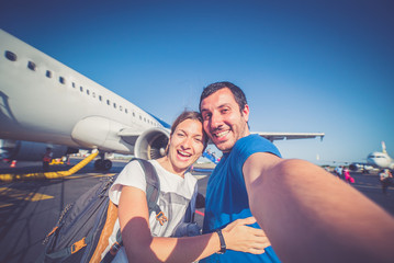 crazy couple take selfie on the airplane during flight before landing.They are a man and a woman, smiling and looking at smartphone. Travel, happiness and lifestyle concepts. 