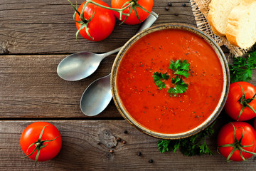 Homemade tomato soup. Top view, table scene on a rustic wood background.