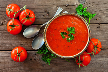 Homemade tomato soup. Top view, table scene with ingredients on a rustic wood background.
