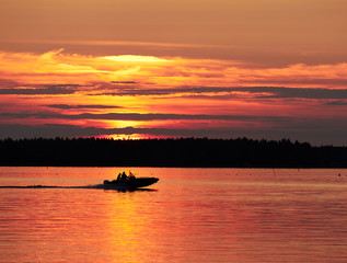 Fototapeta premium A fishing boat on a lake in sunset scene