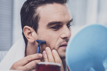 Close up of busy male person that shaving beard
