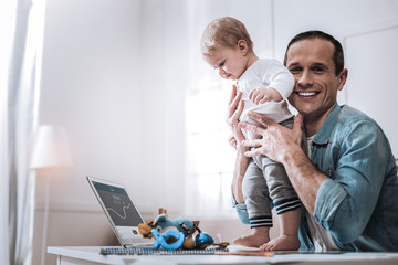 Cheerful positive man holding a baby