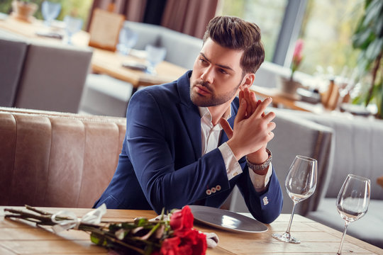 Young Man On Date In Restaurant Sitting With Bouquet Nervous