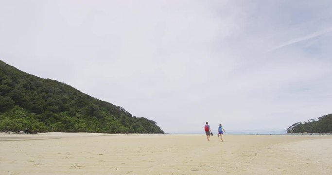 Hiking People. Couple tramping in New Zealand beach travel vacation on Bark Bay beach enjoying holidays in Abel Tasman National Park, New Zealand. RED EPIC SLOW MOTION.