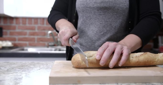 Slider shot of Young millennial woman cutting french bread. Young Millennial woman preparing a meal for her family Shot in ProRes Raw, rec. 2020 HDR 4k 60fps