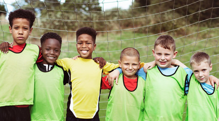 Happy junior football team standing together - obrazy, fototapety, plakaty