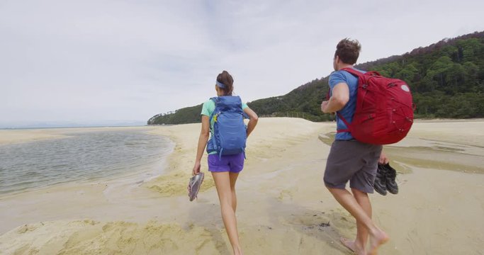 Hiking People. Couple tramping in New Zealand beach travel vacation on Bark Bay beach enjoying holidays in Abel Tasman National Park, New Zealand. RED EPIC SLOW MOTION.