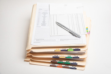A stack of color-coded and numbered patient medical records with blank doctor's office visit form,...