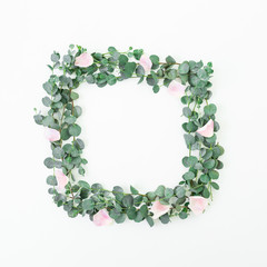 Floral frame of pink roses flowers and eucalyptus branches on white background. Flat lay, top view